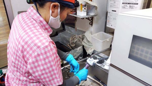 足立区の高齢者宅で家事代行・掃除代行サービス中、ガス台の五徳を丁寧に洗浄している作業風景