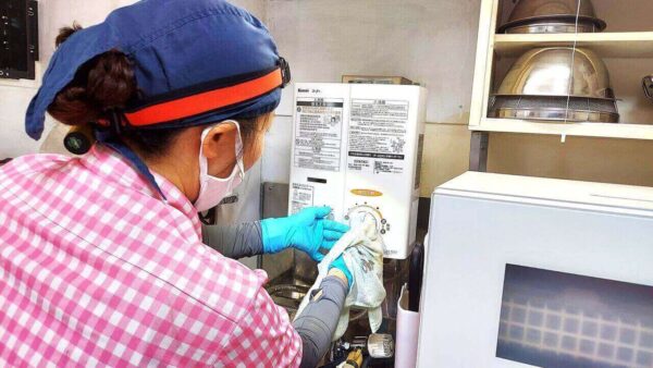 足立区の高齢者宅キッチンで湯沸かし器を家事代行・掃除代行サービスで洗浄している作業中の様子